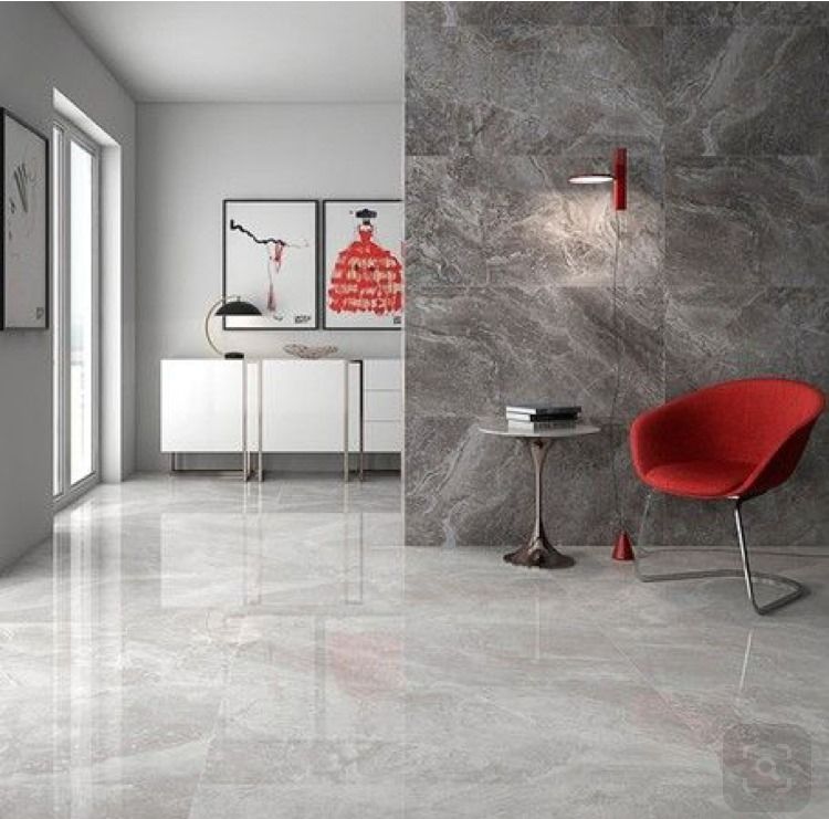 Modern living room with grey marble-look tile, red chair, artwork, and minimalist furniture.