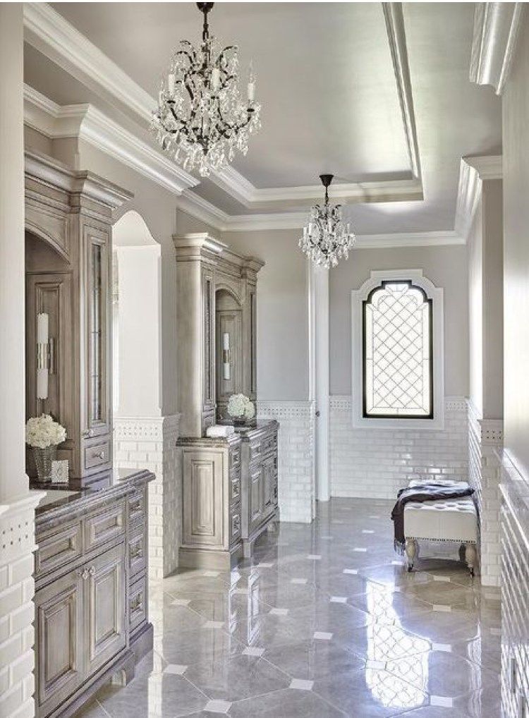 Elegant bathroom with marble floor, chandeliers, and ornate cabinetry.