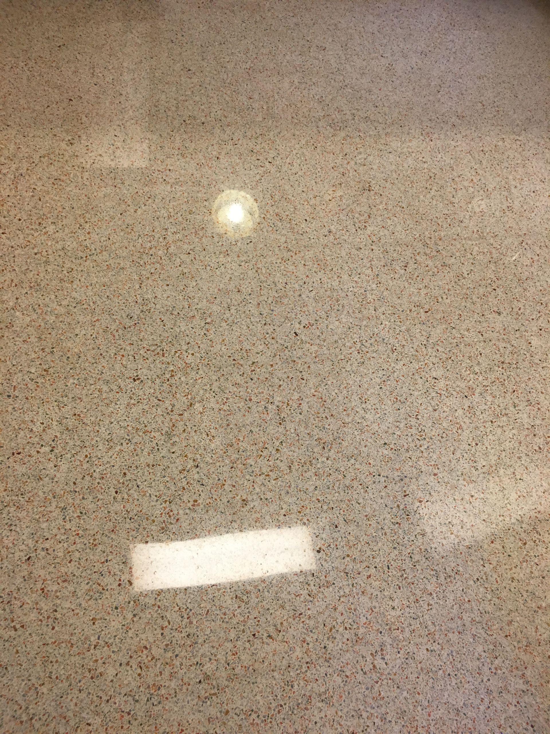 Tan speckled floor with two light reflections.