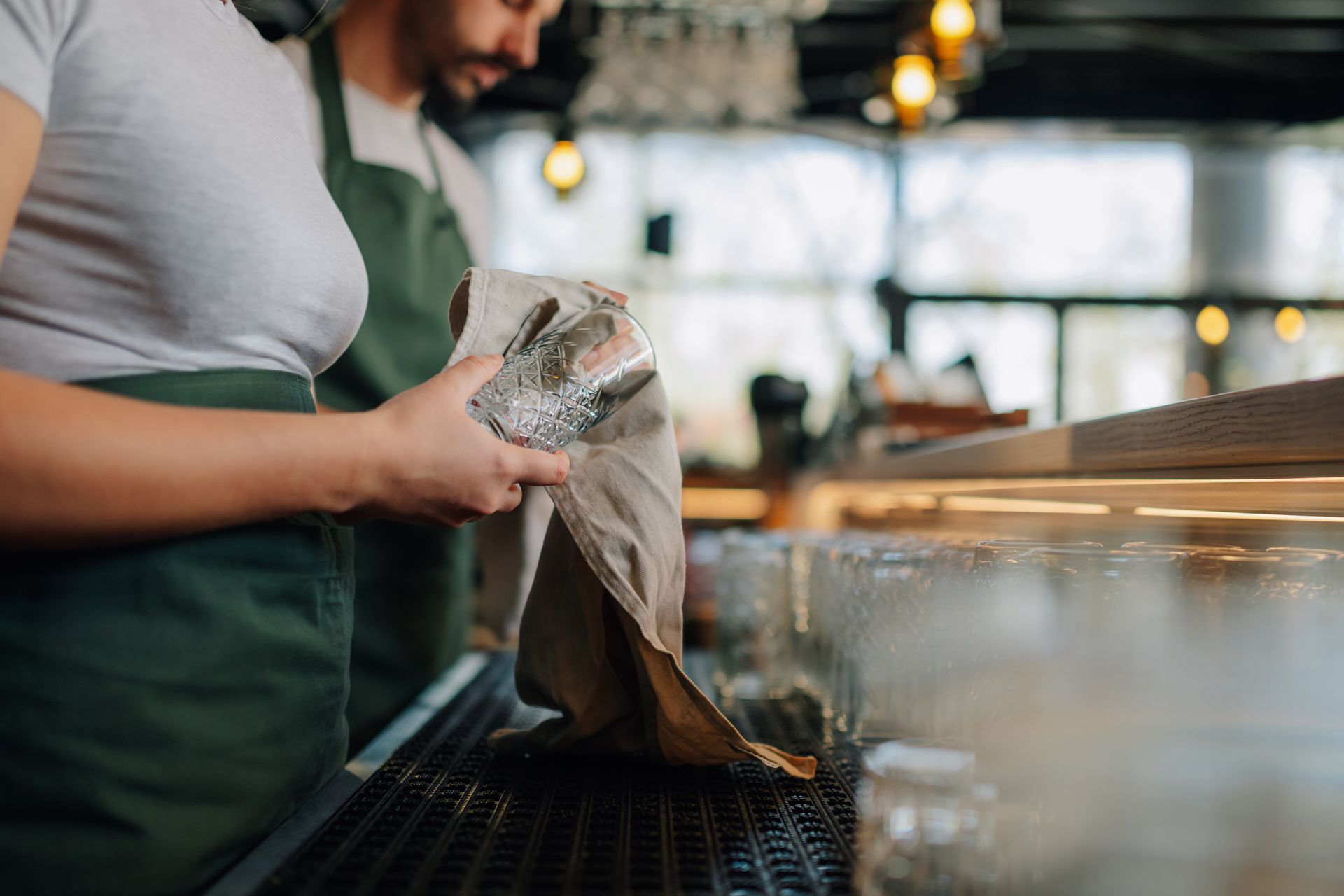 Person wiping a countertop with a cloth in a café kitchen