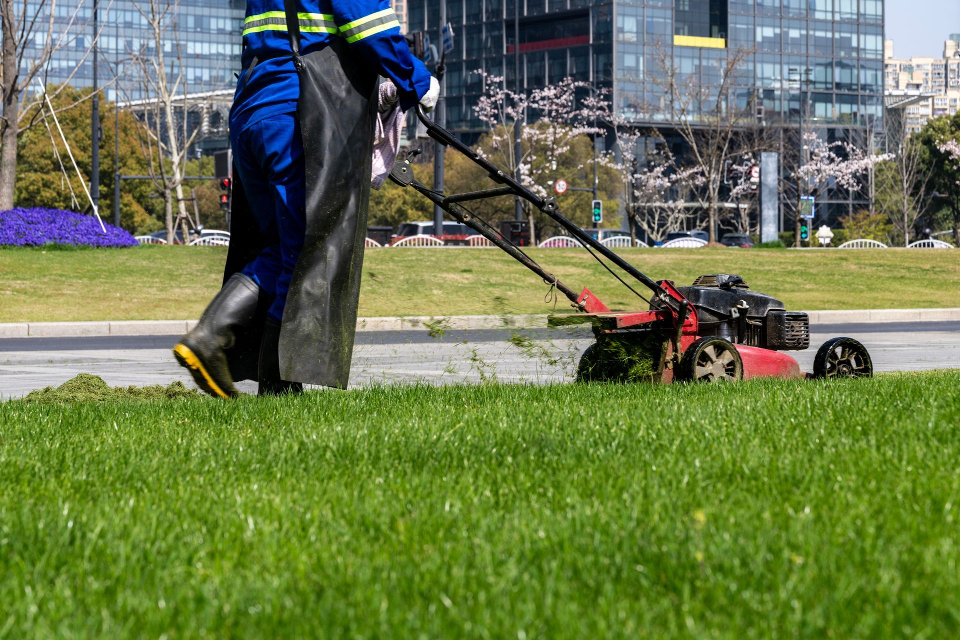 A man mowing grass near a building, demonstrating the work of commercial landscapers in action.