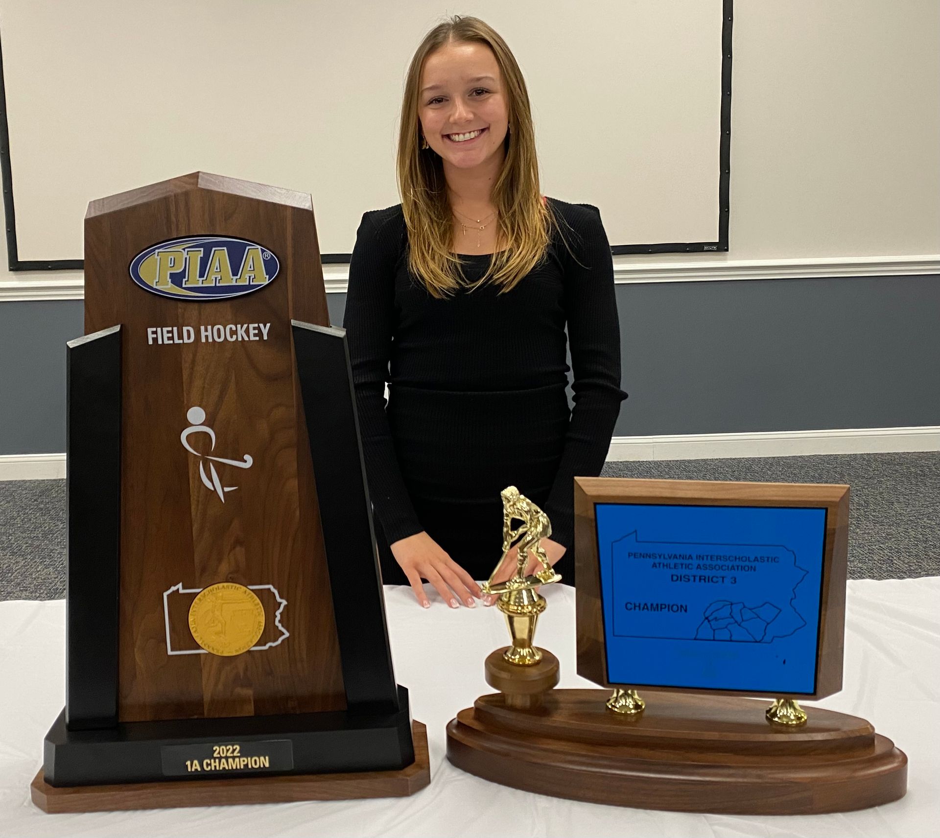 A woman standing next to a trophy that says field hockey
