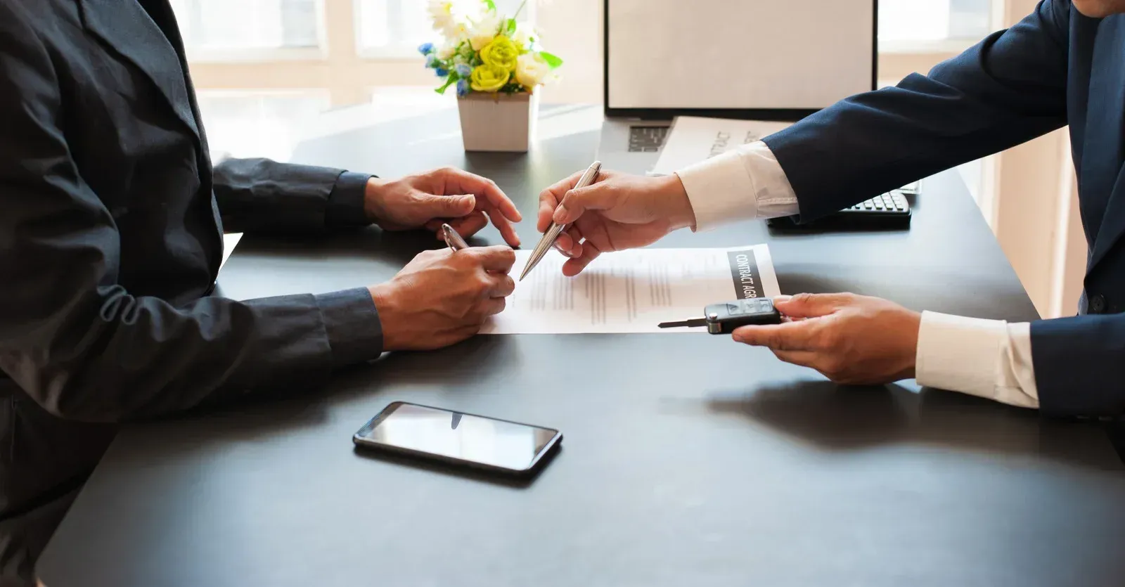 A man and a woman are sitting at a table signing a contract.