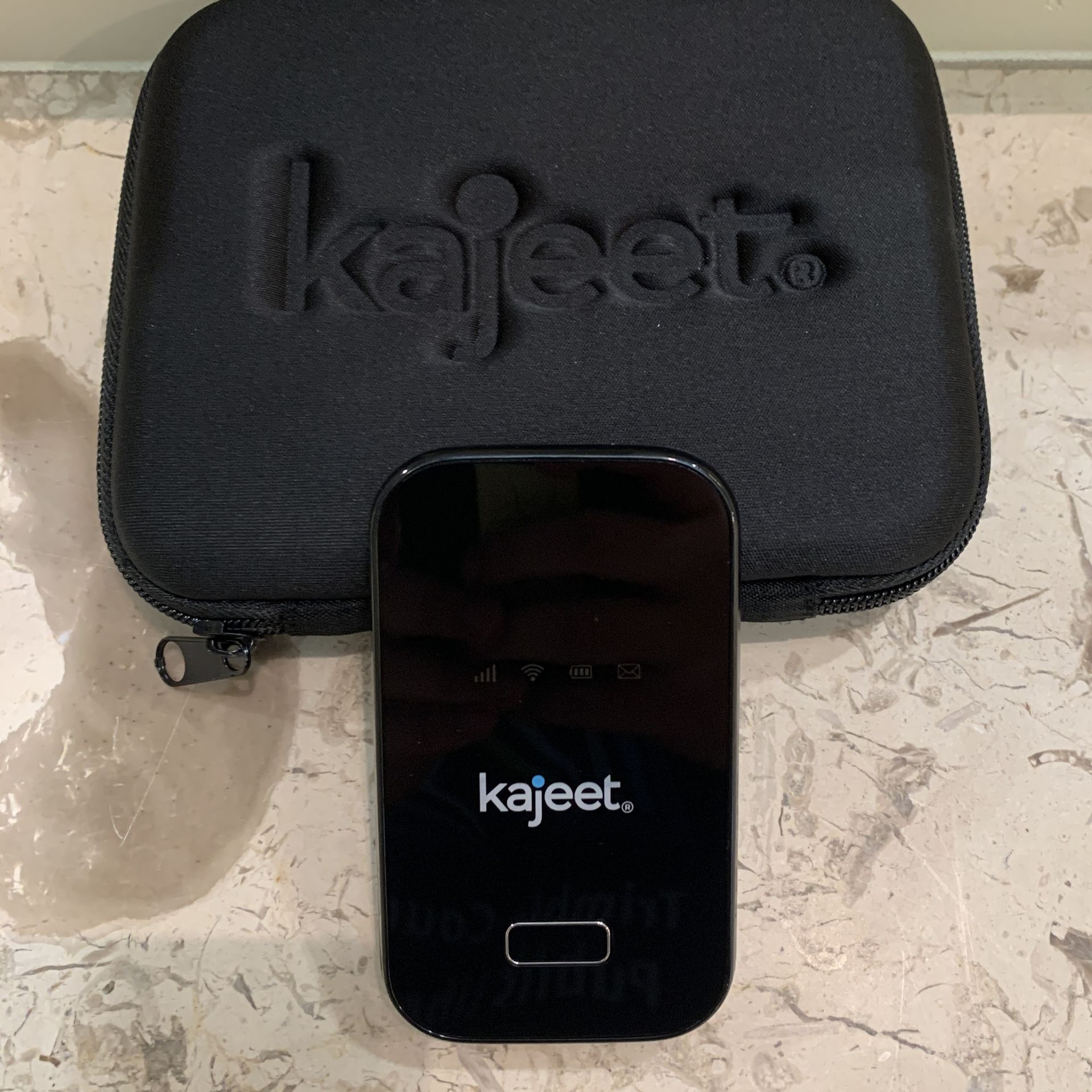 A kajeet hotspot device is sitting against a black case