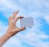 A hand is holding a speech bubble in front of a blue sky