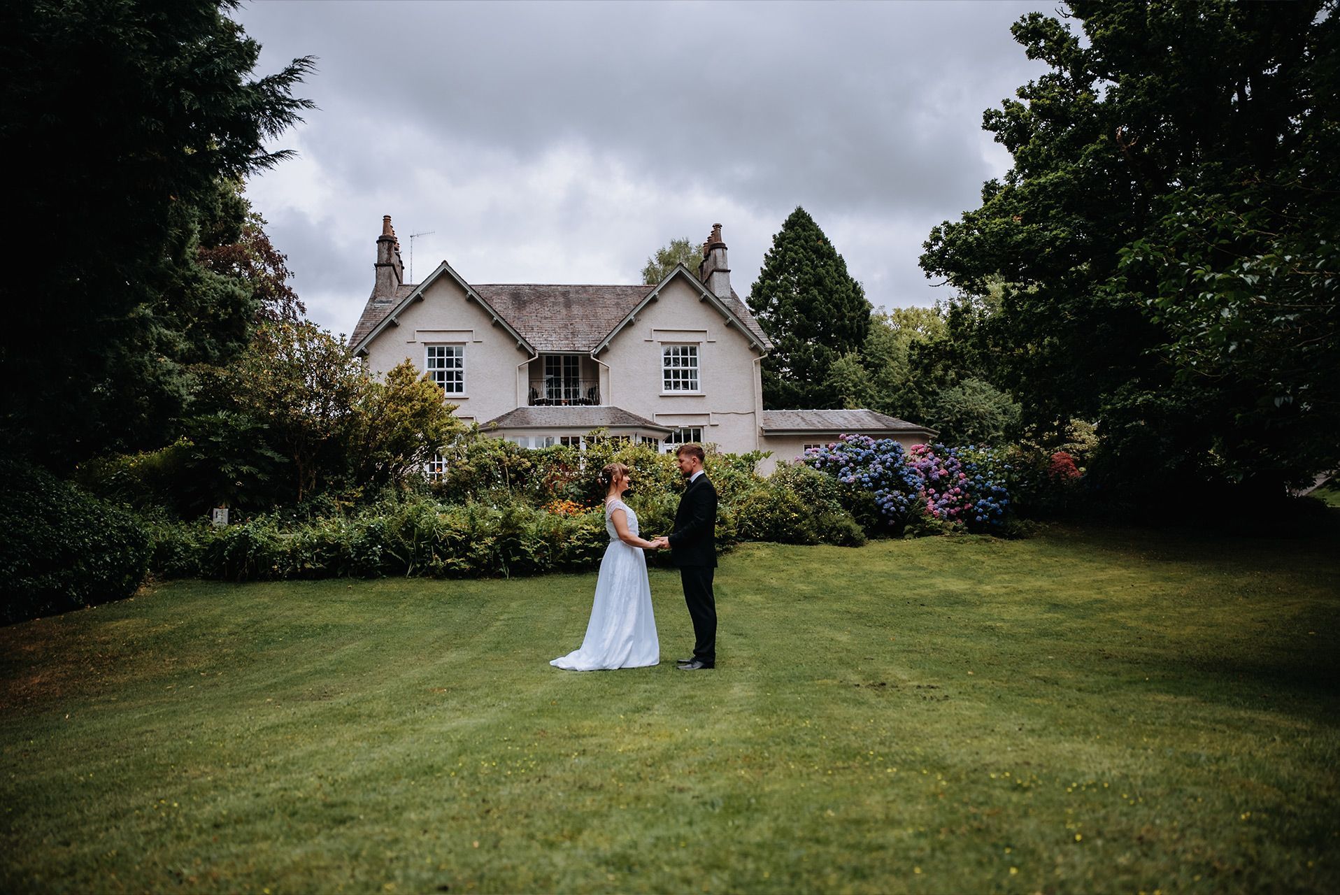 Bride and groom walking through the gardens at Briery Wood Hotel, Windermere