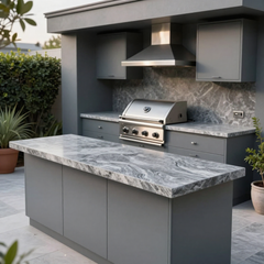Modern outdoor kitchen with built-in stainless grill, gray cabinets, and marble-look countertops under a covered patio