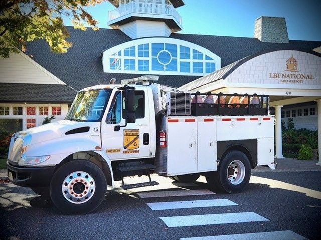 A white utility truck parked in front of a building labeled 