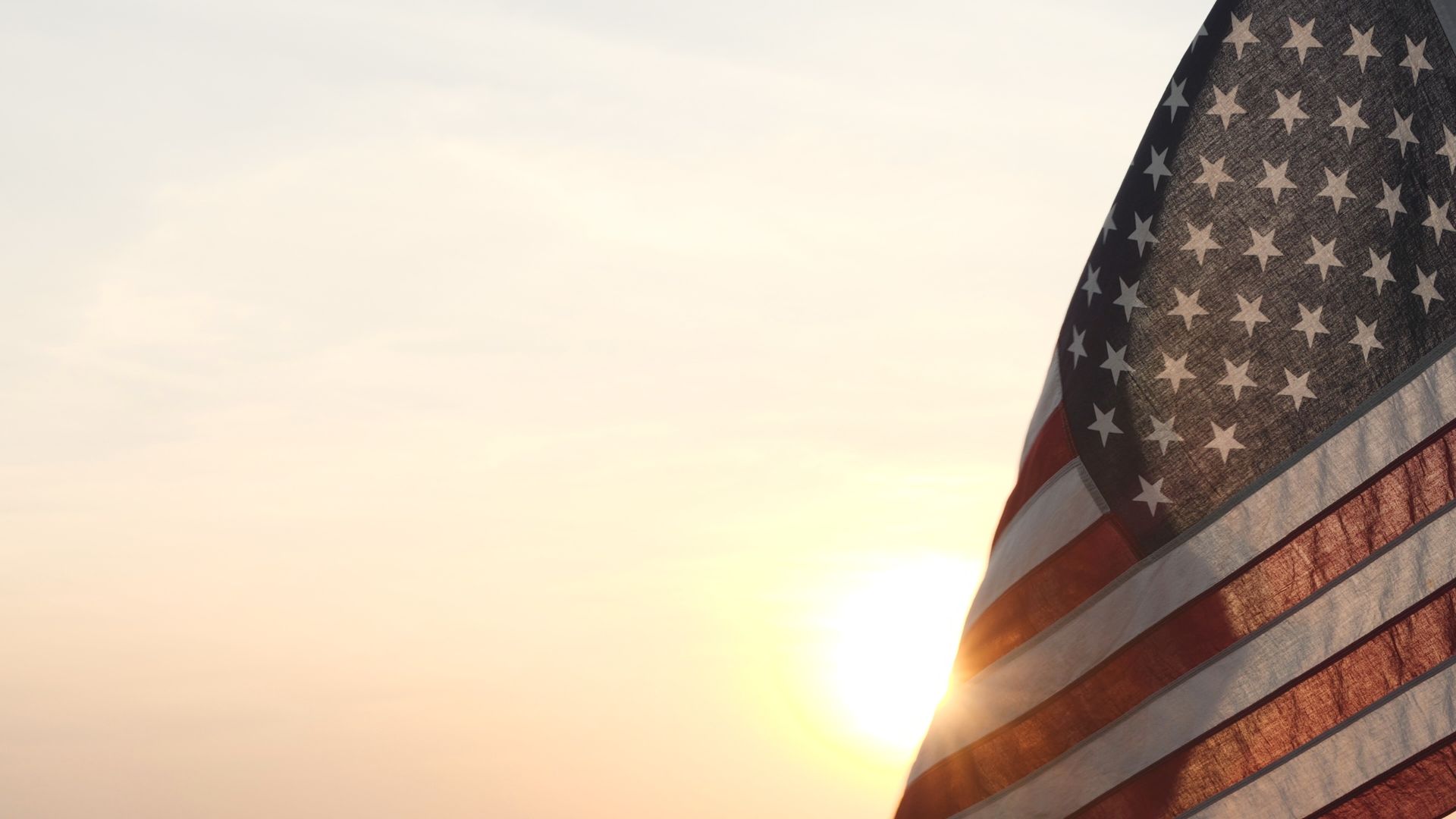 American flag in sunlight against a pale sky