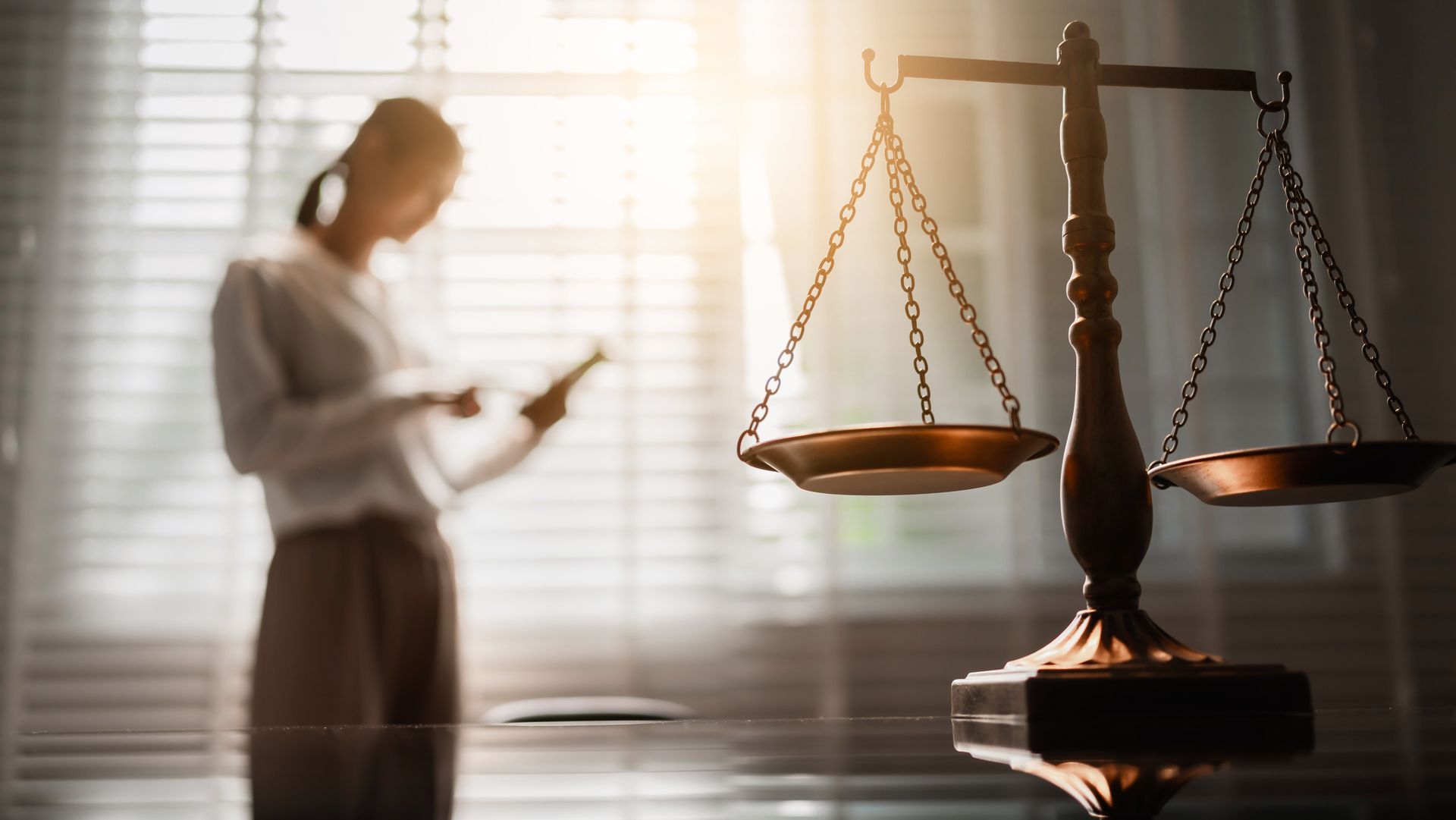 Civil lawyers concept with justice scale in foreground and attorney reviewing legal documents. Civil lawyers concept with justice scale in foreground and attorney reviewing legal documents.