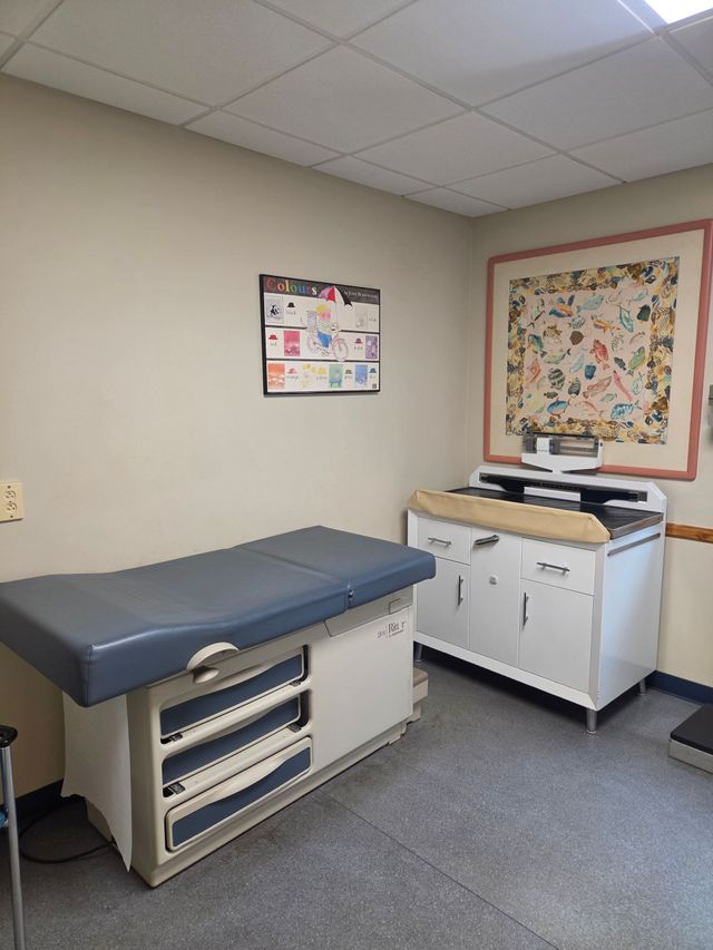 Exam room with an exam table, countertop cabinet, and wall art in a clinical office