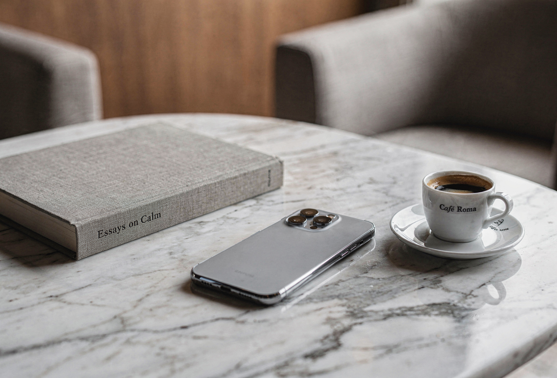 Marble table with a silver phone, coffee cup, and gray book in a modern living room