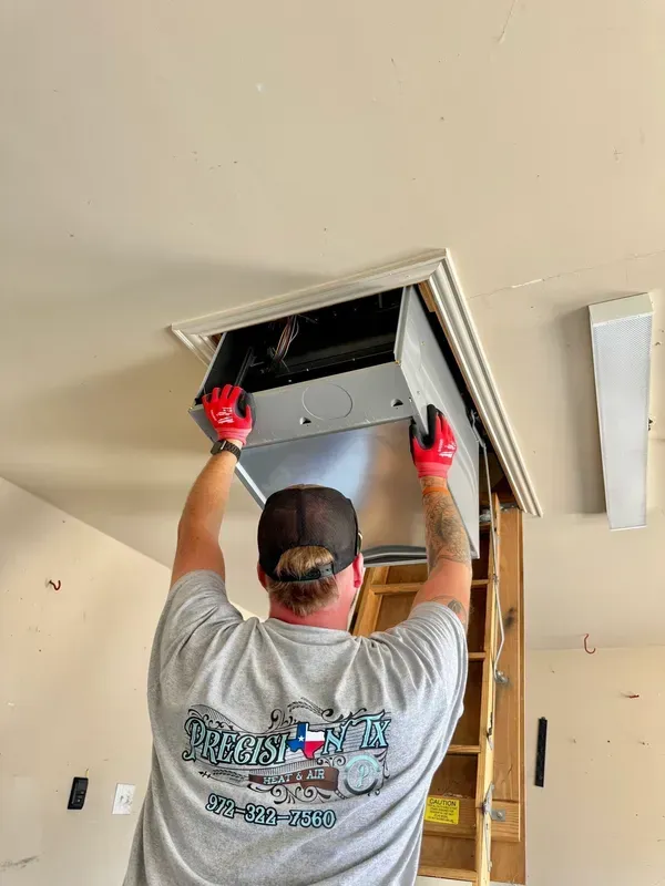 Worker in red gloves installing a ceiling access panel on a ladder.