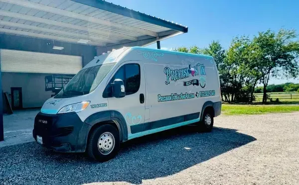 White service van parked beside a building on a sunny day.