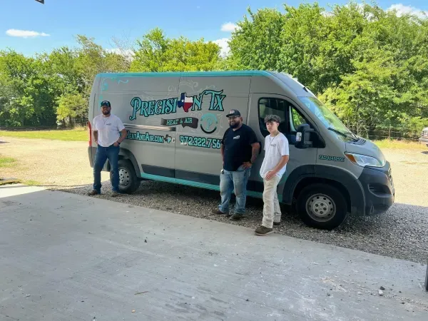 Three people standing beside a white cargo van with colorful graphics in a sunny parking area