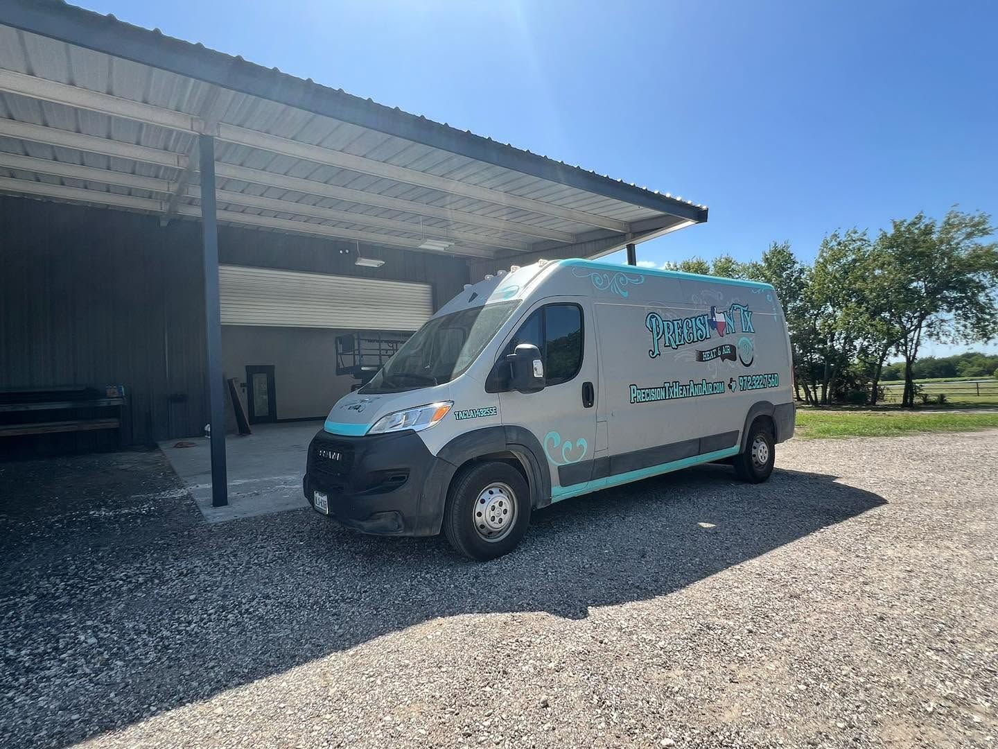 White service van parked under a metal carport on a gravel lot in bright sunlight.