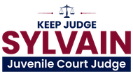 Campaign sign: “Keep Judge Sylvain” in red and blue with scales icon and “Juvenile Court Judge” banner