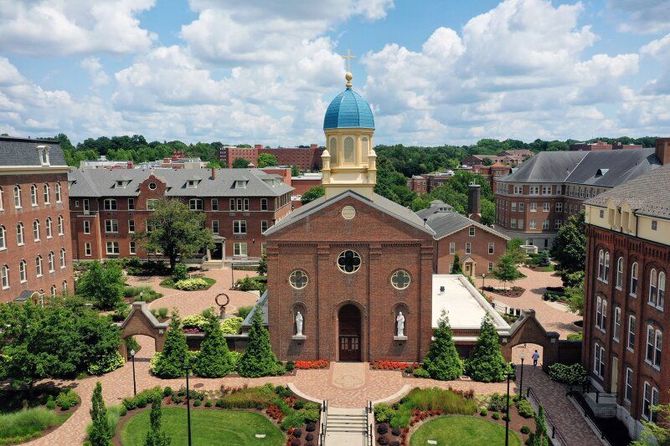 Aerial view of a brick chapel with a blue dome at the University of Dayton campus courtyard, surrounded by brick buildings.
