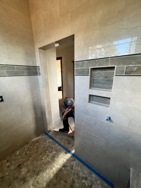 A man is kneeling in a bathroom next to a door.