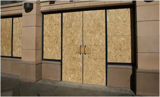 A building with a lot of windows covered in plywood.