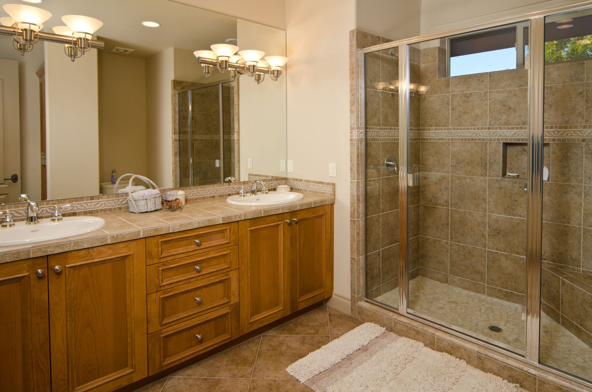 A bathroom with two sinks and a walk in shower.
