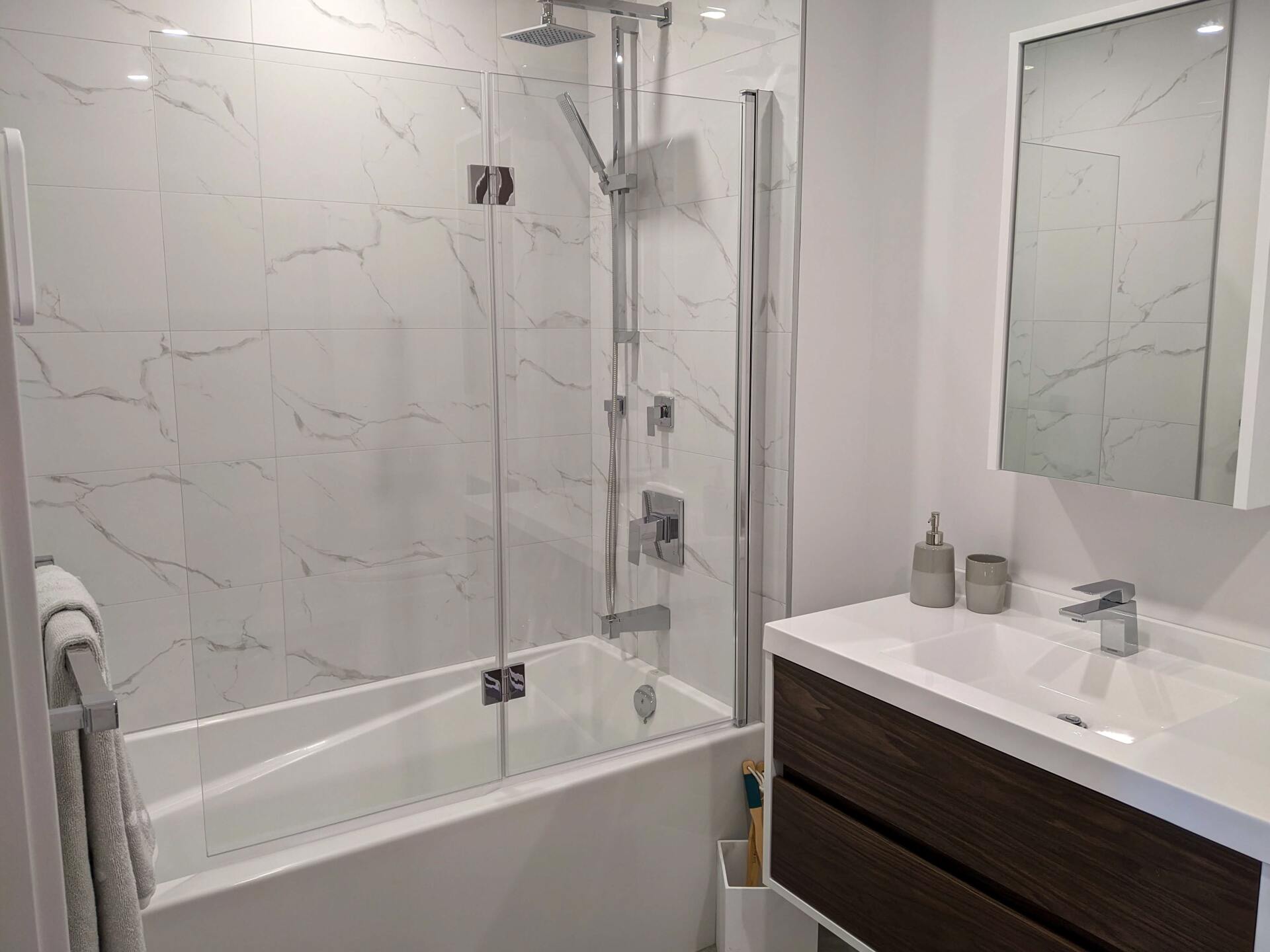 A bathroom with a bathtub , sink , mirror and shower.
