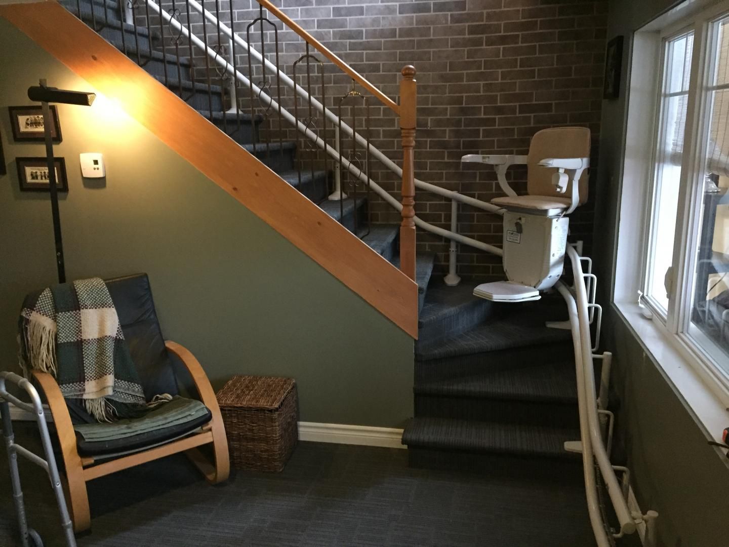 Palier d'escalier intérieur avec chaises, mur de briques et fenêtres dans un petit hall d'entrée