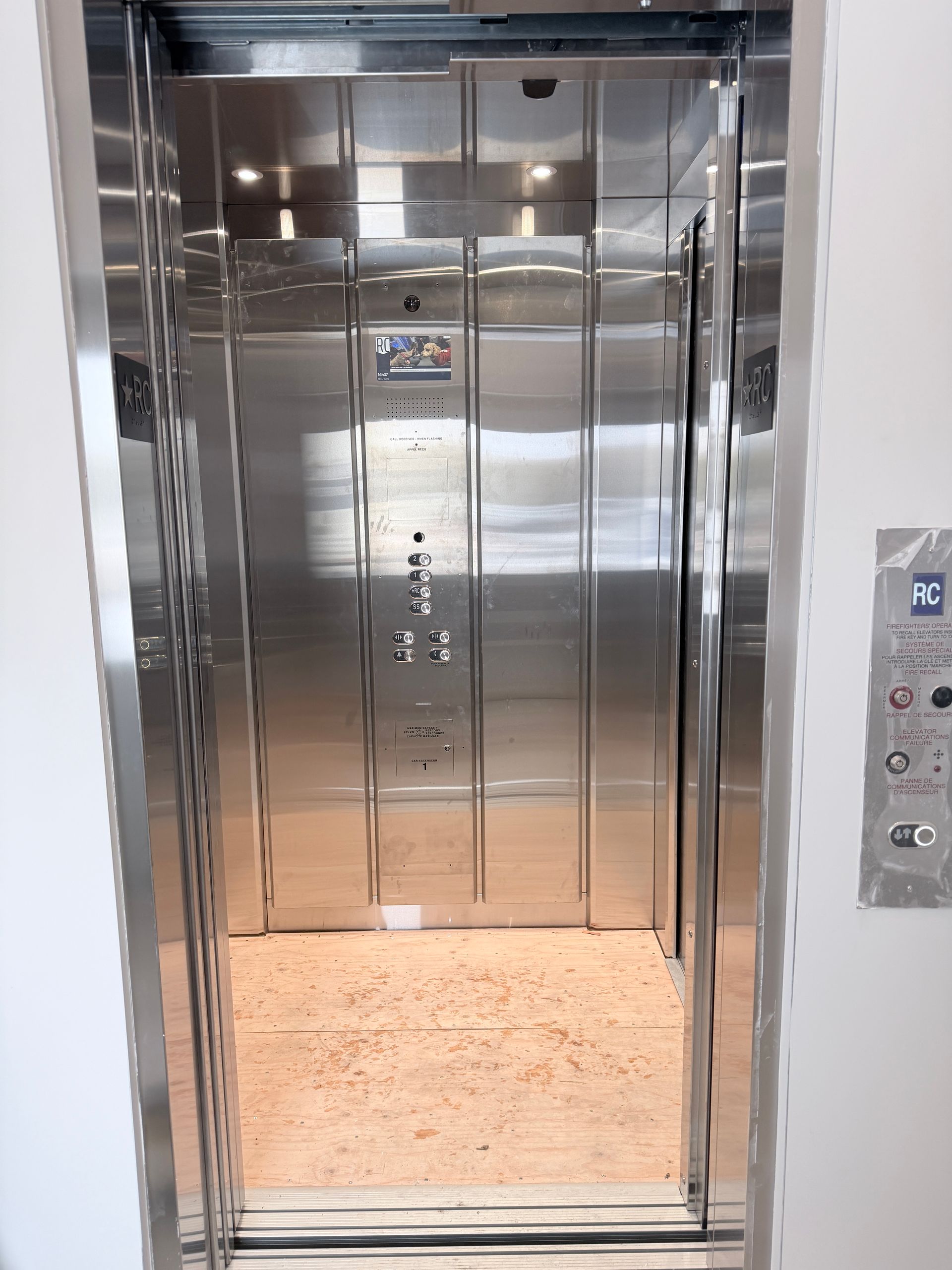 Ascenseur en acier inoxydable avec portes ouvertes et panneau de commande à droite