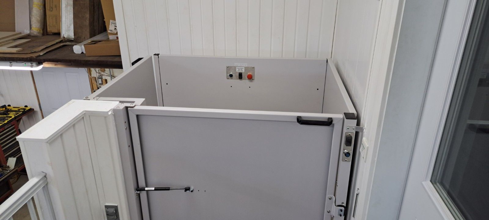Porte d'ascenseur blanche et panneaux muraux dans un espace extérieur étroit et clos, vu d'en haut