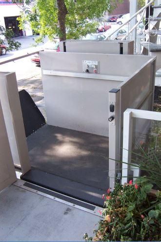 Monte-escalier extérieur avec plateforme au bas d'une rampe d'accès au porche, à côté de plantes en pot