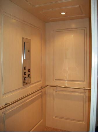 Intérieur d'un ascenseur beige avec panneau de commande miroir et parois lambrissées