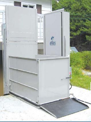 Ascenseur extérieur pour fauteuils roulants avec structure métallique grise et plateforme en forme de rampe à côté d'une maison