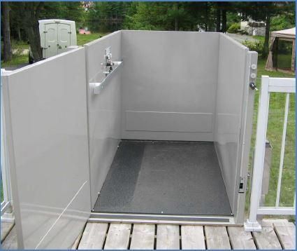 Plateforme élévatrice extérieure accessible avec murs gris, portes ouvertes et sol antidérapant