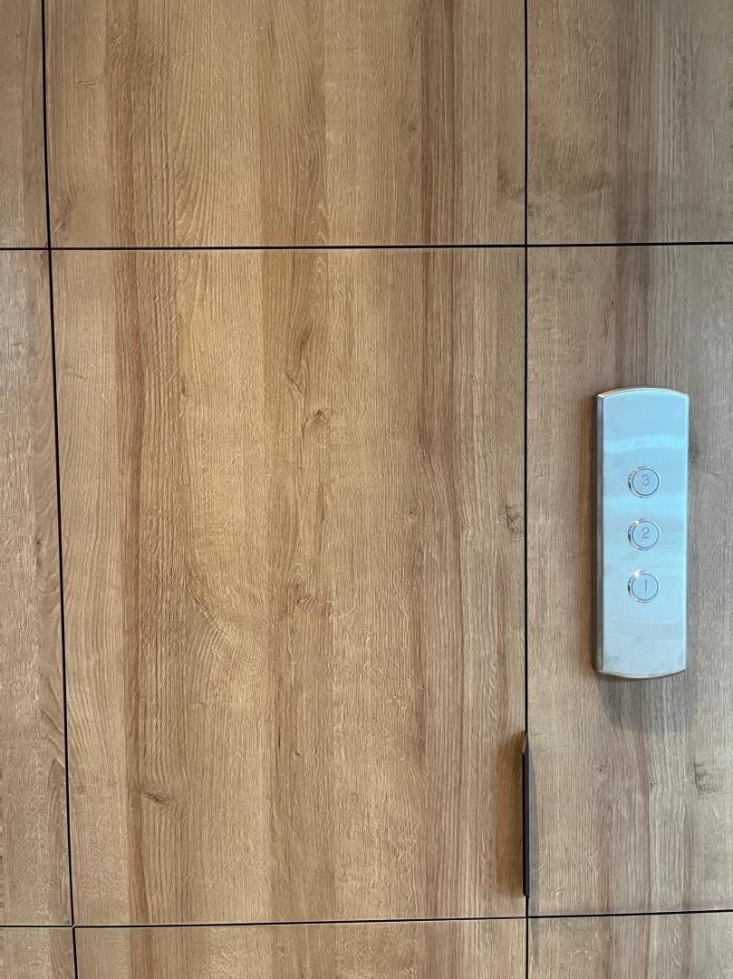 Sol en bois avec une télécommande murale blanche étroite sur le côté droit.