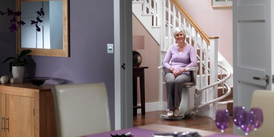 Femme assise dans un monte-escalier à côté d'un escalier intérieur d'une maison