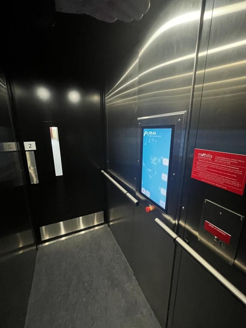 Intérieur d'ascenseur moderne avec murs noirs, panneaux en acier inoxydable et panneaux de commande bleus et rouges