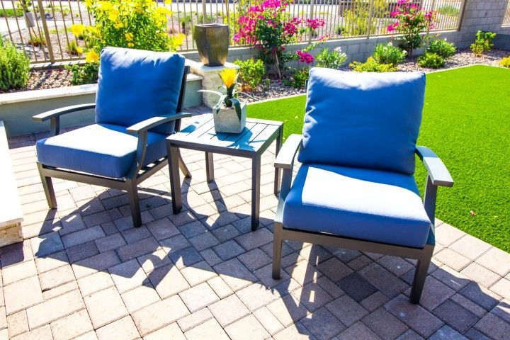 Two blue chairs and a small table on a patio.