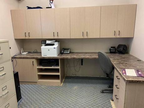 Office space with light wood cabinets, a printer, desk, file cabinet, and a chair.
