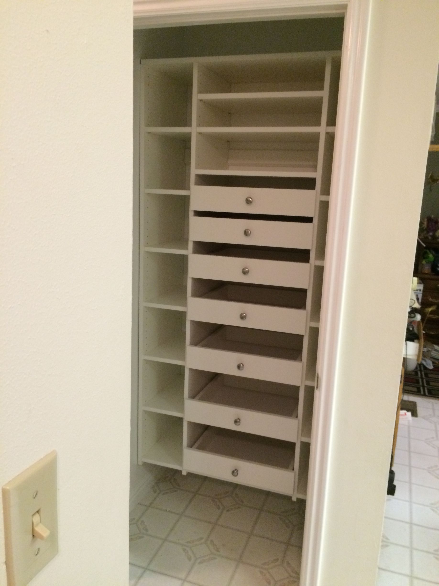 White closet with shelves and drawers, visible from a doorway.