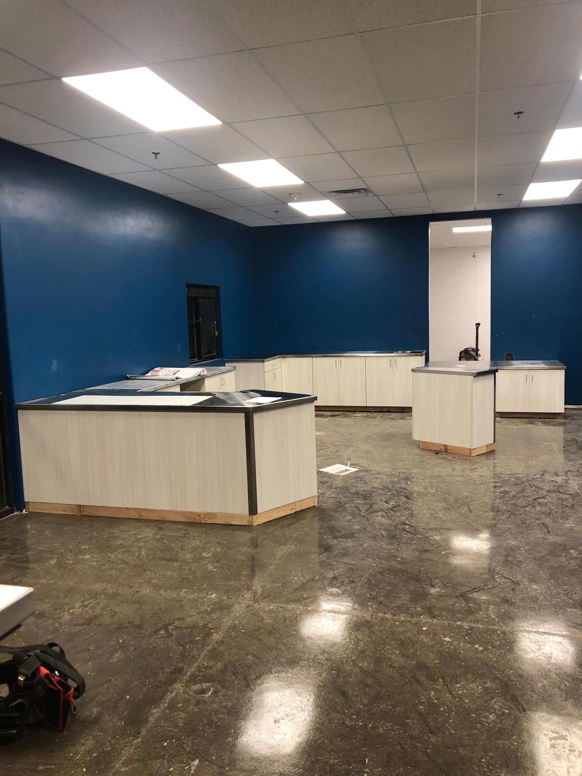 Empty retail space with white and blue walls, wood counters, and a concrete floor.