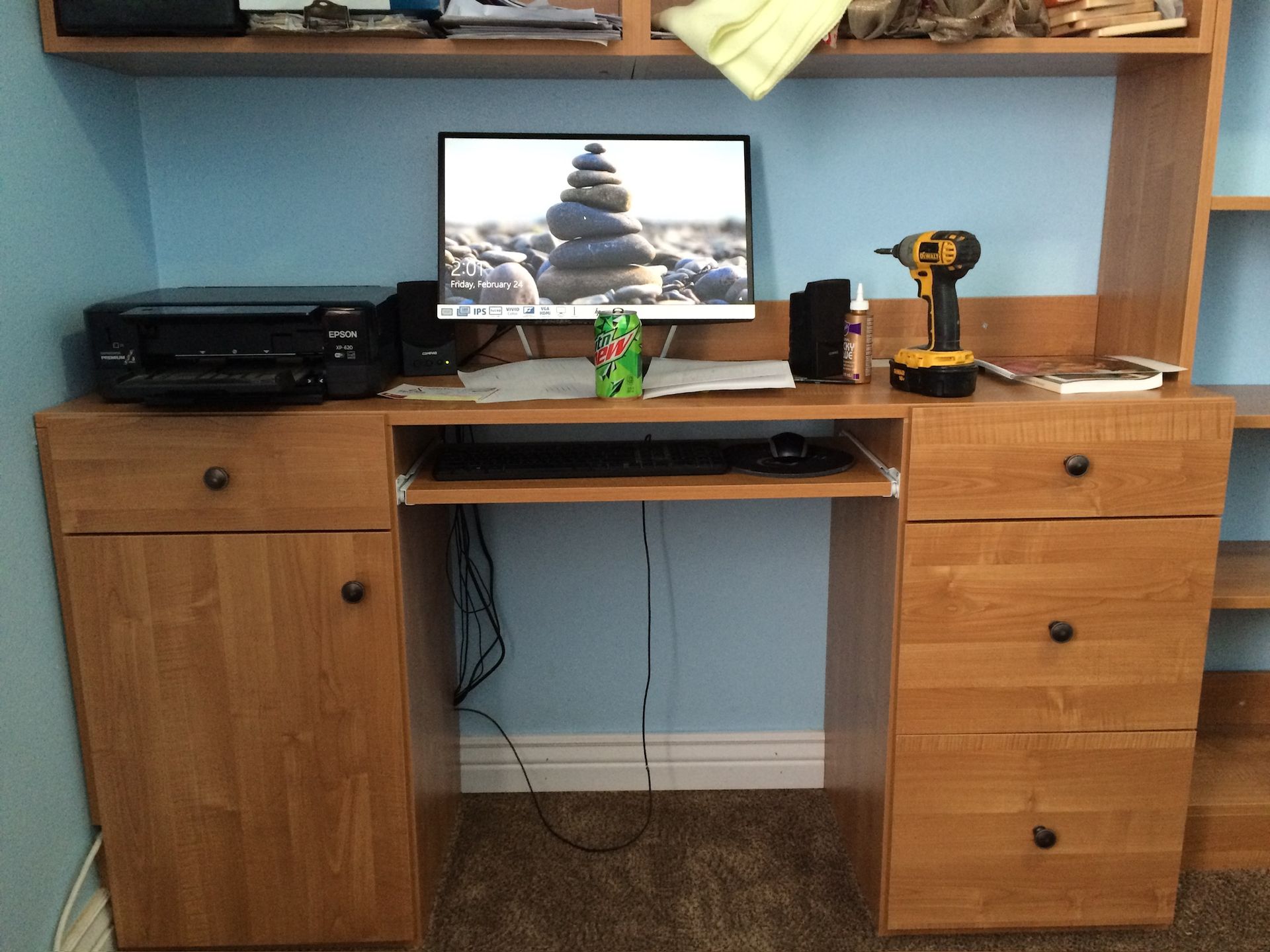 Wooden desk with computer, printer, tools, and drink.