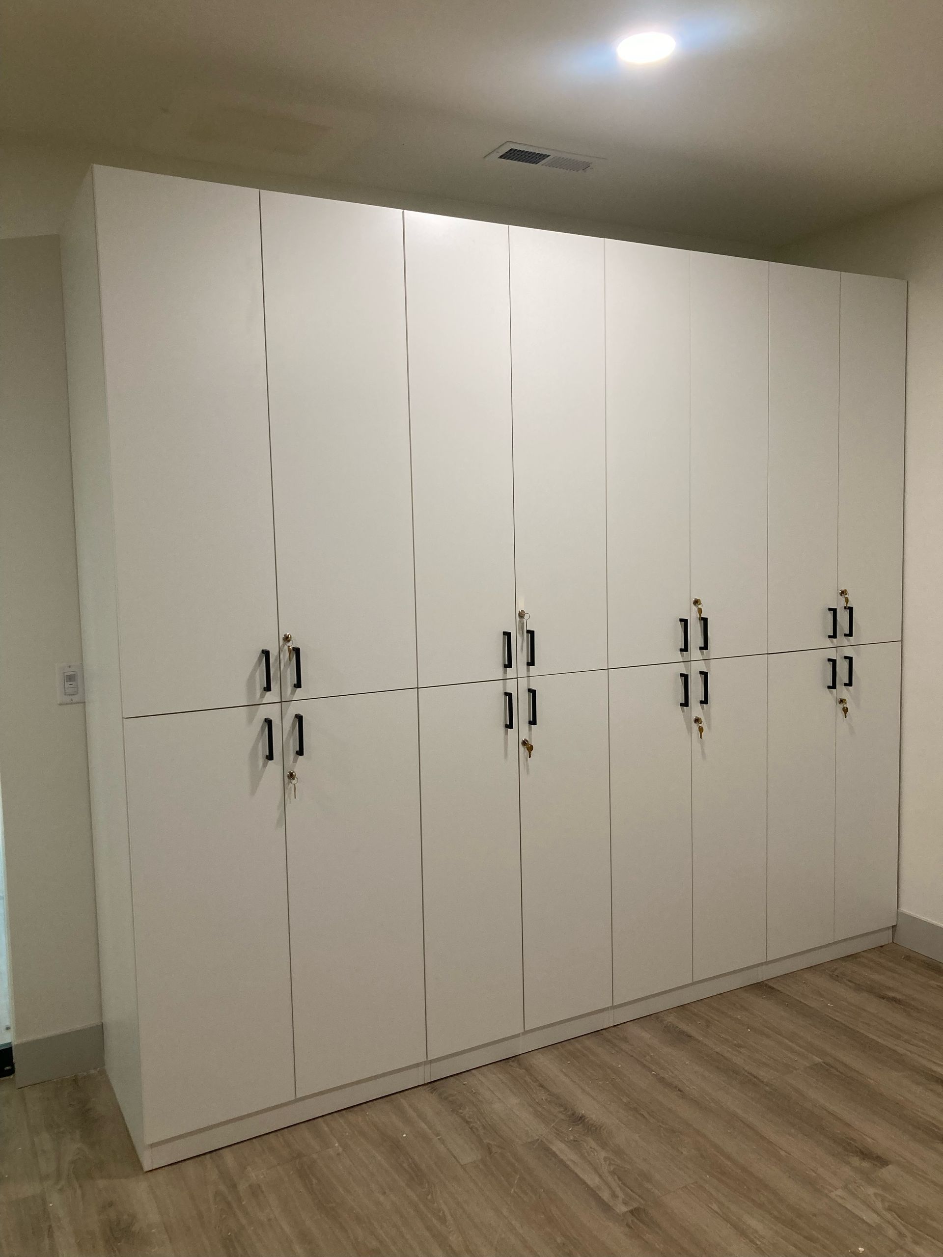 White closet doors in a room with wooden flooring and a ceiling light.