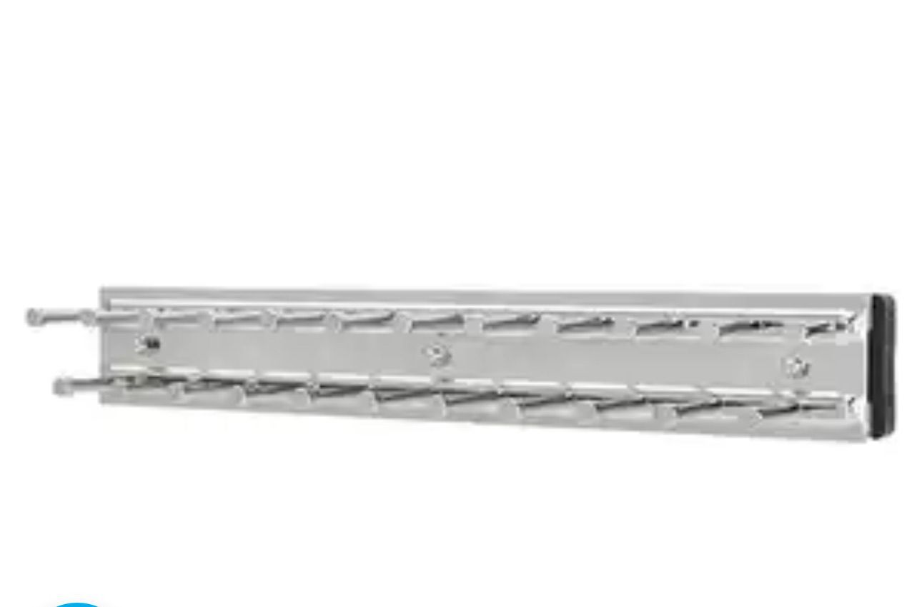 Silver tie rack with angled slots for hanging ties, mounted on a wall.