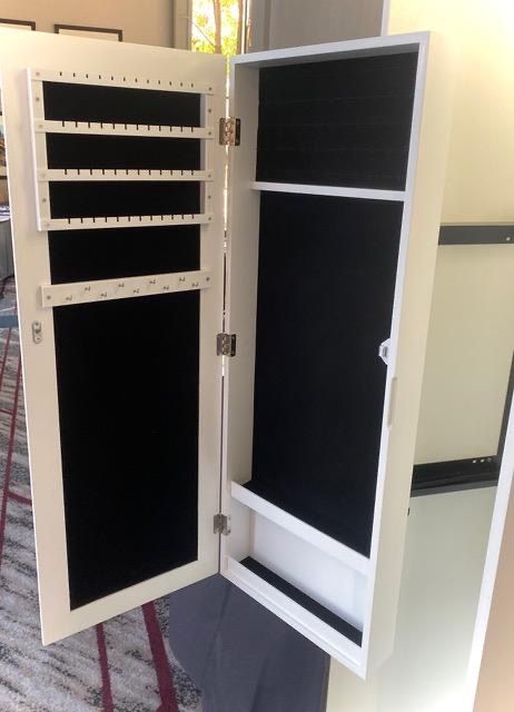 White jewelry armoire open, revealing black felt interior and earring/necklace storage.