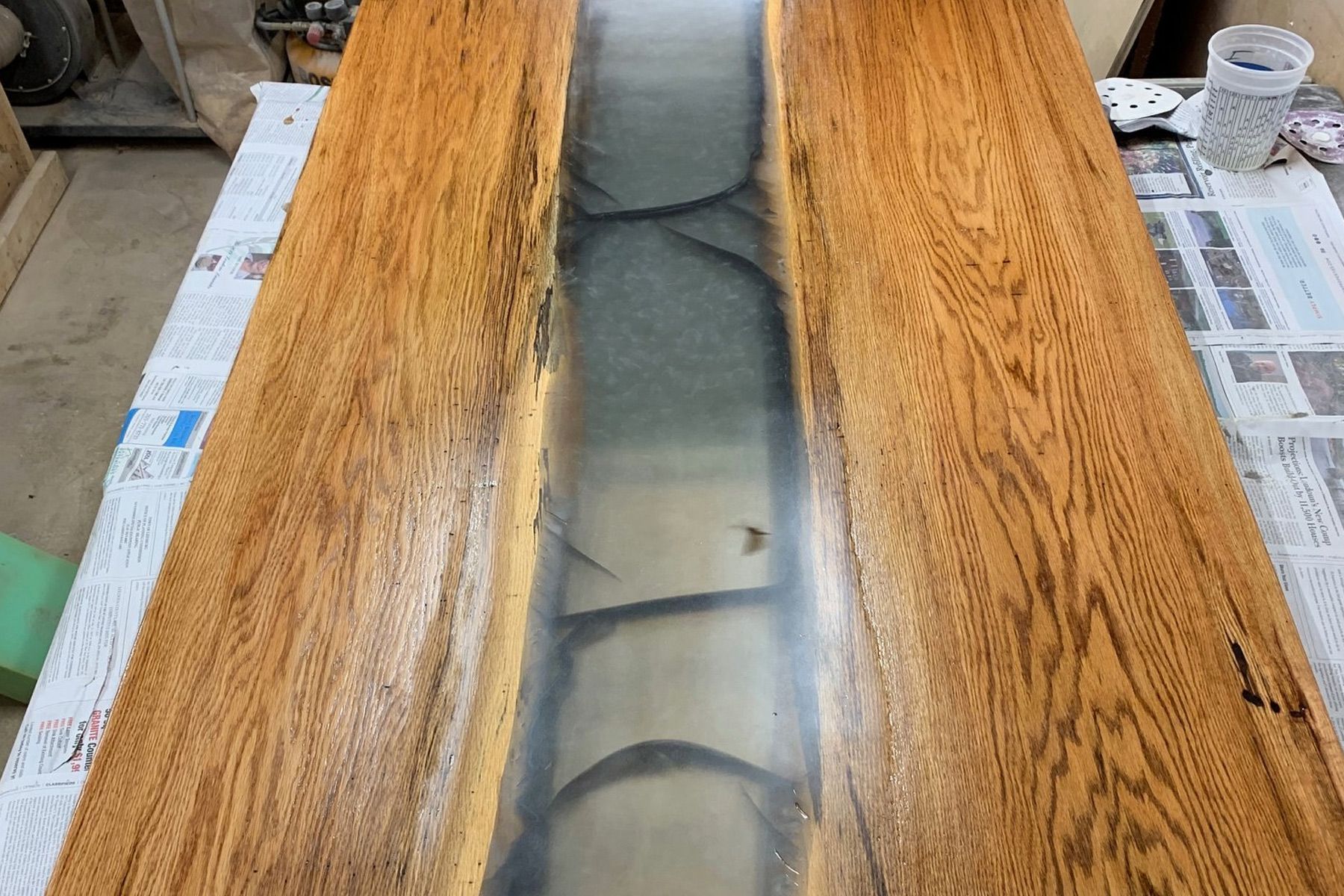 Wooden table with epoxy river in the center; wood is brown; epoxy is gray, cracked.
