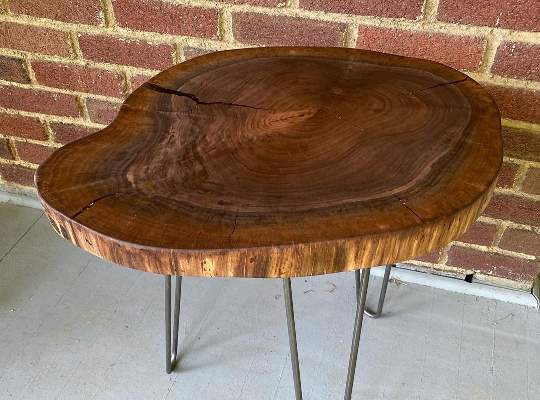 Live-edge wooden table with hairpin legs against a brick wall.