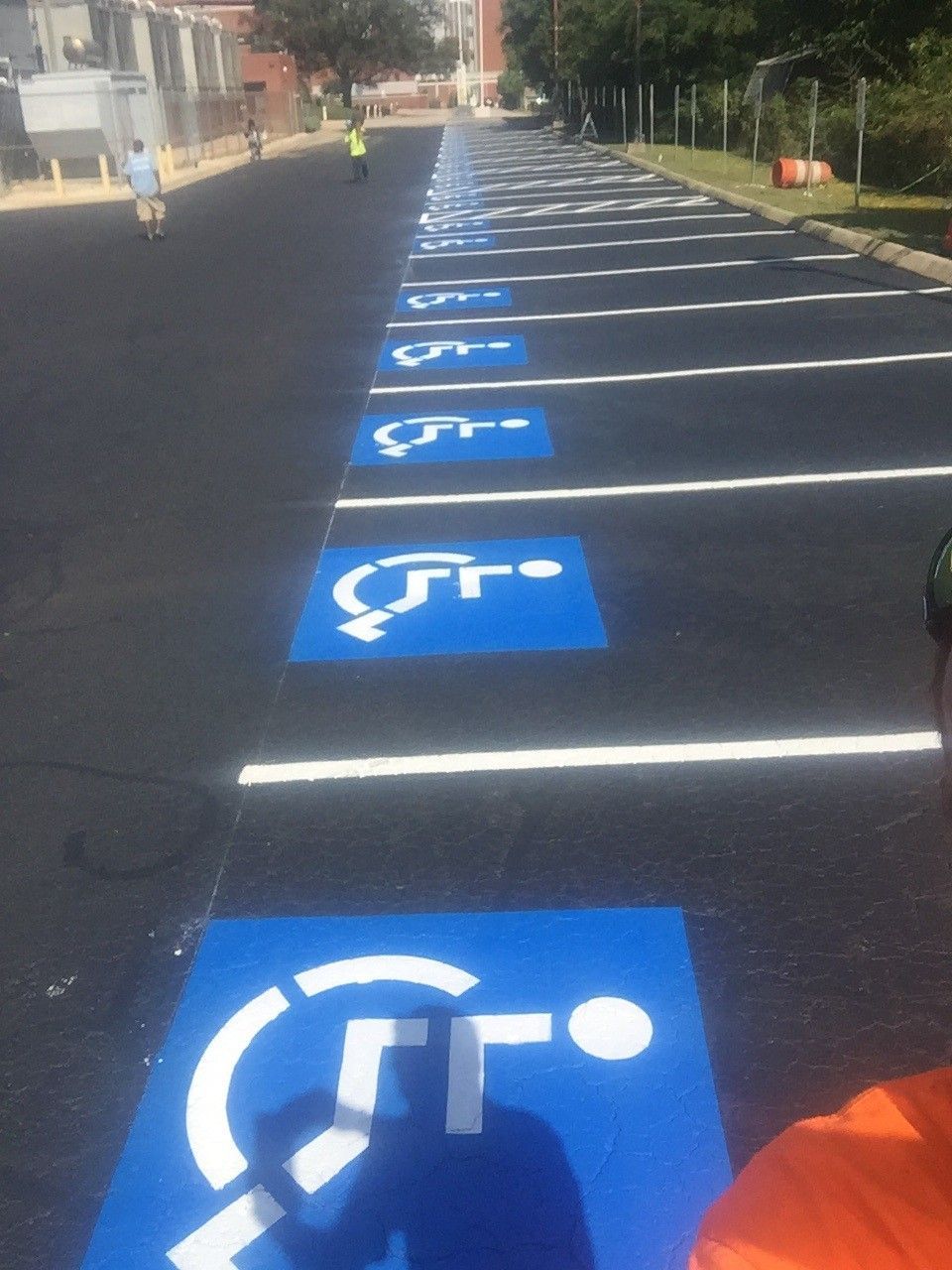Blue accessible parking spaces lined up in a lot, viewed in perspective along the curb.