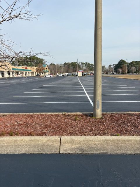 Empty parking lot with a utility pole in the center and buildings in the distance.
