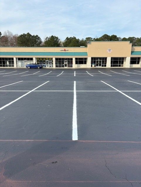 Empty shopping center parking lot with white lane markings in front of storefronts