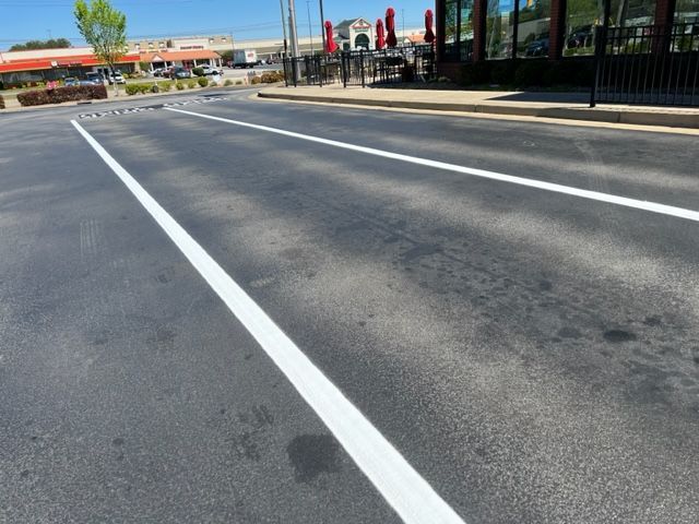 Empty multi-lane road with white lane markings on a sunny day, buildings and flags in the distance